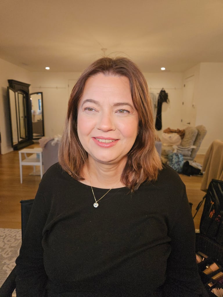 Pro-Age transformation after - woman with shoulder-length reddish-brown hair wearing a black top and necklace smiling at camera