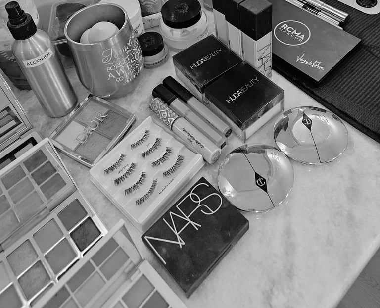 Organized collection of makeup and beauty products including cosmetics, brushes, false eyelashes, eyeglasses, and perfume in black and white